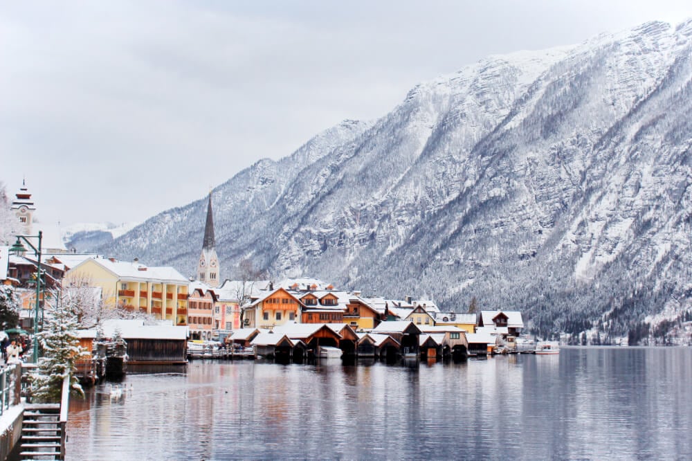 Snowy Hallstatt, Austria in front of a mountain, reflected in the icy lake.