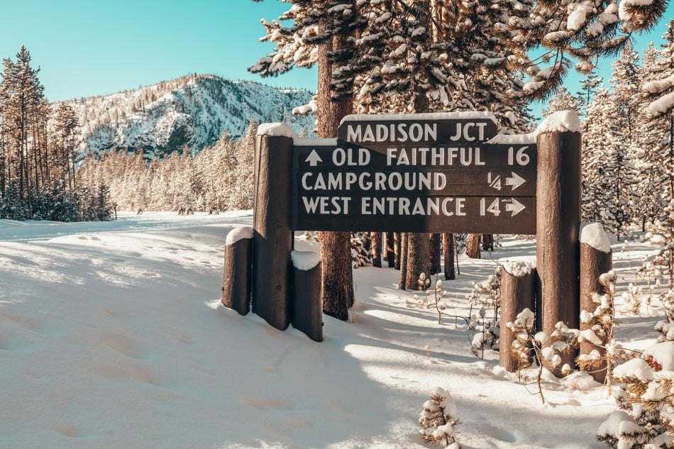 Madison Junction southbound directional sign surrounded by snow in Yellowstone National Park