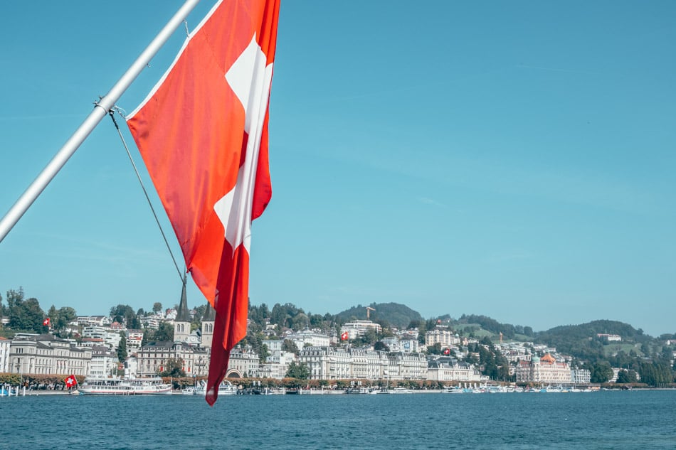 swiss flag and view of the city of lucerne from boat